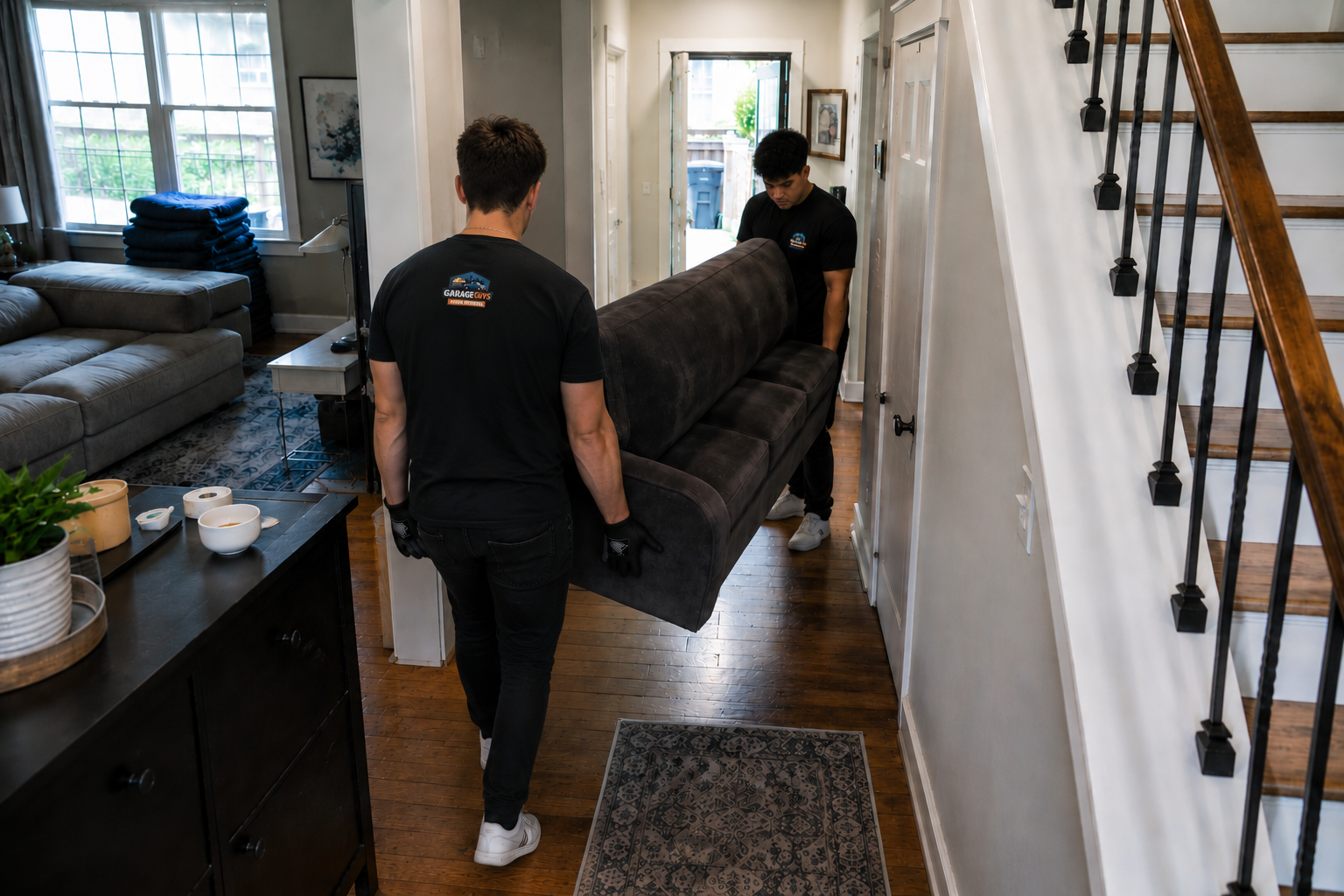GarageGuys crew carrying a couch through a Seattle home hallway